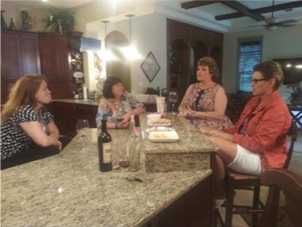 Image of 5 friends sitting around a home bar drinking wine